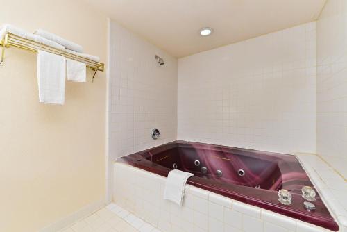 baño con bañera roja y azulejos blancos en America's Best Value Inn & Suites, Atlanta - Morrow, en Morrow