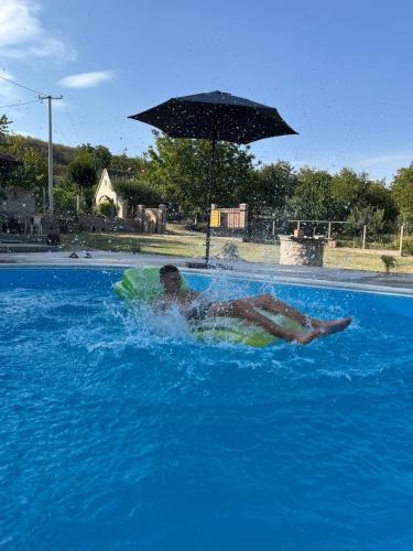 a man swimming in a pool with an umbrella at Vikend house Cvrcak in Slankamenački Vinogradi