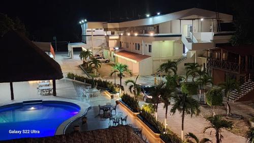 an outdoor swimming pool in front of a building at night at Hotel Luna Caribe in Chetumal