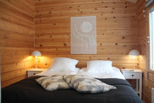 una camera da letto con due letti con pareti in legno e due lampade di Villa Hilda, cottage by the lake a Posio