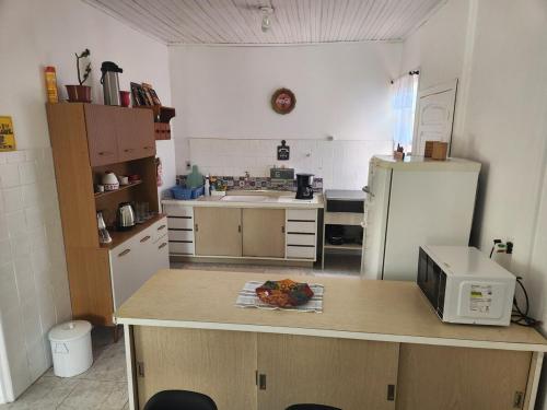 a kitchen with a counter with a microwave and a refrigerator at Casa próxima a praia in Capão da Canoa