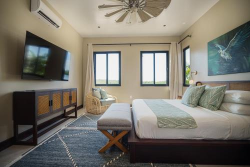 a bedroom with a bed and a flat screen tv at Prana Maya Island Resort in Placencia Village