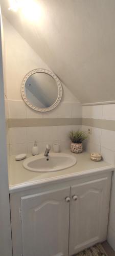 une salle de bain avec un lavabo blanc et un miroir dans l'établissement Les Jardins de Virginie, à Archignac