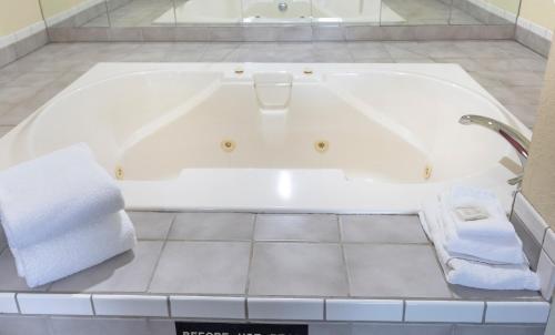 a white bath tub with towels in a bathroom at Super 8 by Wyndham Big Rapids in Big Rapids