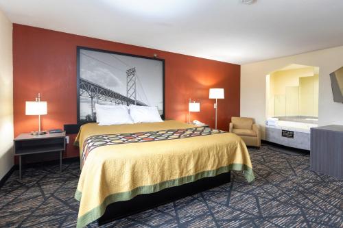 a hotel room with a large bed and a chair at Super 8 by Wyndham Big Rapids in Big Rapids