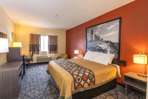 a hotel room with a large bed and a desk at Super 8 by Wyndham Big Rapids in Big Rapids