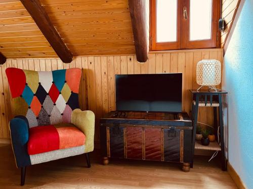 a living room with a chair and a flat screen tv at Apartamento La Buhardilla del Boscache in San Juan de Plan