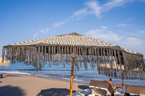 an umbrella on a beach with chairs and the ocean at Zen Suites & Spa in Perissa