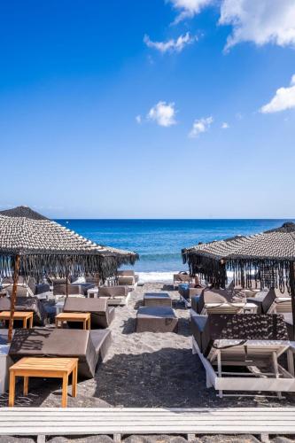 a beach with chairs and umbrellas and the ocean at Zen Suites & Spa in Perissa