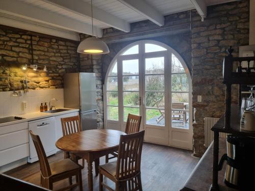 une cuisine avec une table et des chaises et une fenêtre dans l'établissement Refuge Kreiz An Avel - Plage de Pors Carn - Pointe de la Torche - Vue mer - Sea View - Meerblick - 4 Pers, à Penmarcʼh