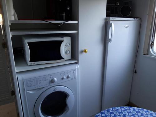 a kitchen with a microwave and a washing machine at Bungalow à la campagne in Senonches