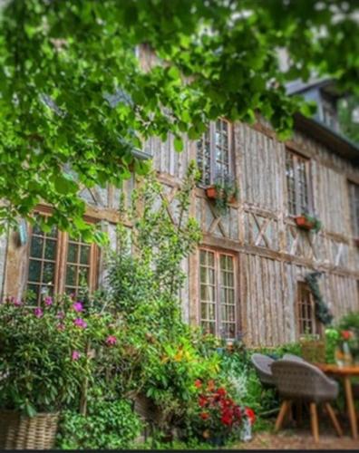 un bâtiment avec un bouquet de fleurs devant dans l'établissement LA MAISON DE LALETTE - B&B et Workshop Photo durant la belle saison -, à Gruchet-Saint-Siméon