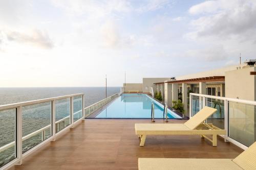 a balcony with a swimming pool and the ocean at Luxury Beachfront Stay - Sheki Sands in Wattala