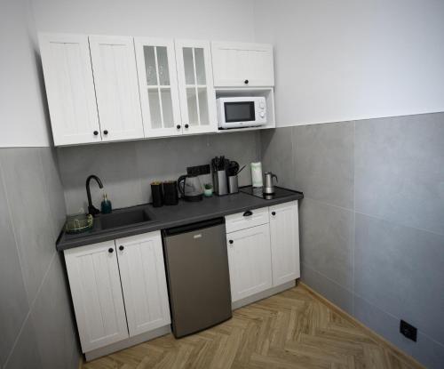 a kitchen with white cabinets and a microwave at Apartament Antresola Przemyśl in Przemyśl