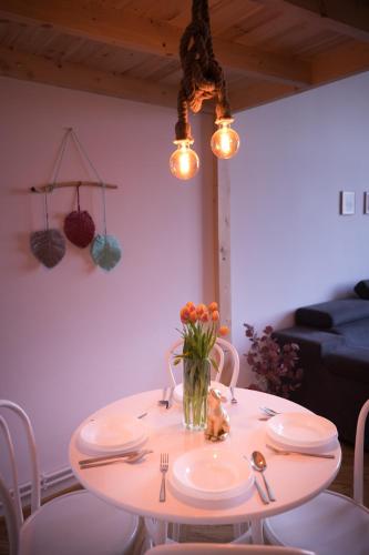 a table with plates and a vase of flowers on it at Apartament Antresola Przemyśl in Przemyśl
