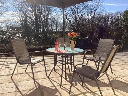 a patio table with three chairs and an umbrella at Quoit X Barn in Tiverton