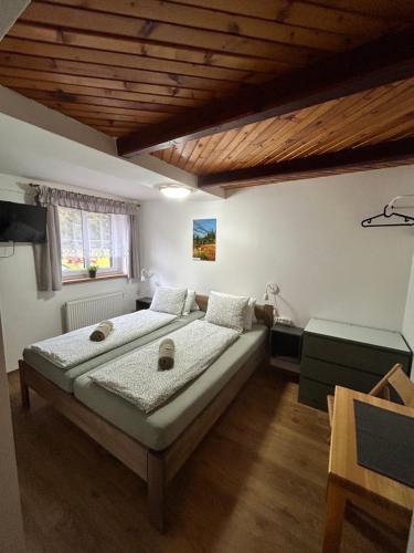 a bedroom with a large bed and a wooden ceiling at Pension Hones in Horská Kvilda