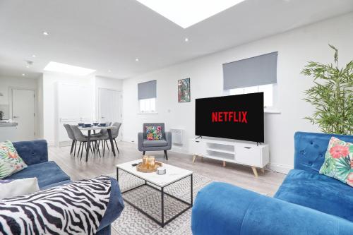 a living room with a blue couch and a tv at Chelmsford City Centre Modern Duplex With Parking, Wi-Fi & Netflix in Chelmsford