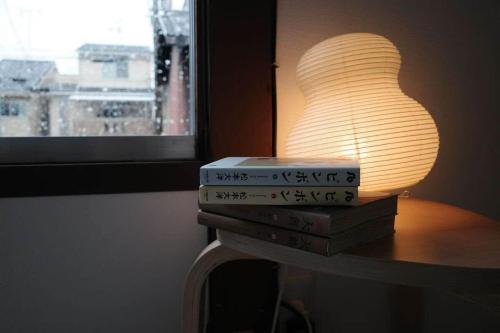 a stack of books sitting on a table next to a lamp at Traditional Japanese architecture heiansya in Kyoto