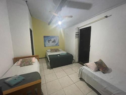 a room with two beds and a ceiling fan at Recanto da Praia Rasa in Búzios