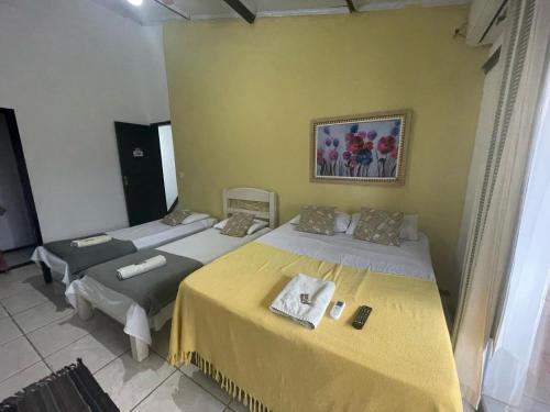 two beds in a room with yellow walls at Recanto da Praia Rasa in Búzios