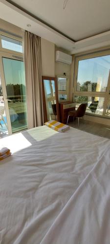 a bedroom with a large white bed and a desk at Hurghada Mirage Bay Hotel & Aquapark in Hurghada