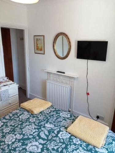 a bedroom with a bed and a television on the wall at Regis Lodge Guest House in Bognor Regis