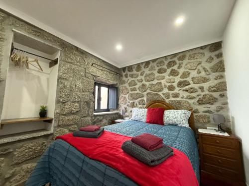a bedroom with a stone wall with a bed at Casa Carlinhos da Carreira in Terras de Bouro