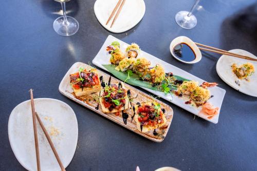 three plates of food sitting on a table with chopsticks at Zen Suites & Spa in Perissa