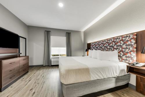 a hotel room with a bed and a flat screen tv at Hawthorn Extended Stay by Wyndham College Station in College Station