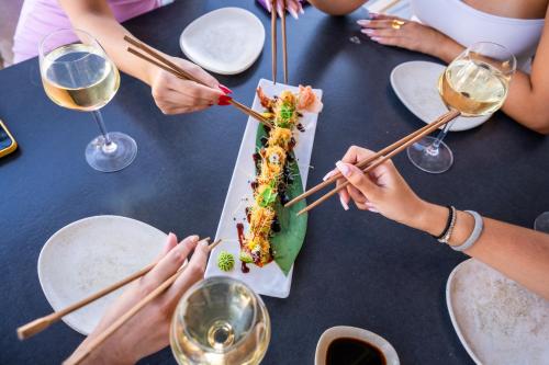 a group of people sitting around a table eating food with chopsticks at Zen Suites & Spa in Perissa