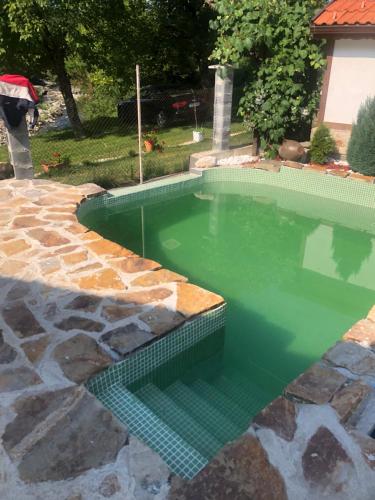 a swimming pool with green water in a yard at Къща За Гости Двата Ореха in Protopopintsi