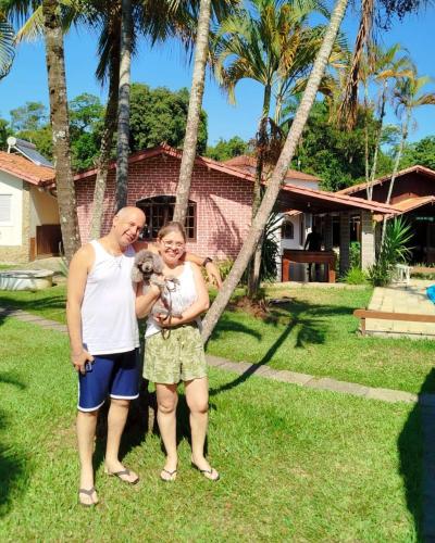 a man and a woman holding a dog in front of a house at Pousada Tapera in Penedo