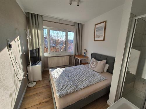 a small bedroom with a bed and a television at Pension Ostsee-Strand in Börgerende-Rethwisch