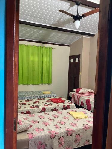 a bedroom with two beds and a green window at Hospedagem da Miss in Lençóis