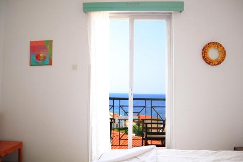 a bedroom with a window with a view of the ocean at Atlantis Rooms in Ágios Konstantínos