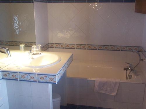 uma casa de banho com um lavatório e uma banheira em Hôtel Les Bernards em Praz-sur-Arly