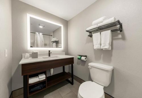 a bathroom with a toilet and a sink with a mirror at Hawthorn Extended Stay by Wyndham College Station in College Station
