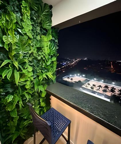 a room with a green wall with a chair and a window at Charmoso e tecnológico! Piscina panorâmica! in Sorocaba
