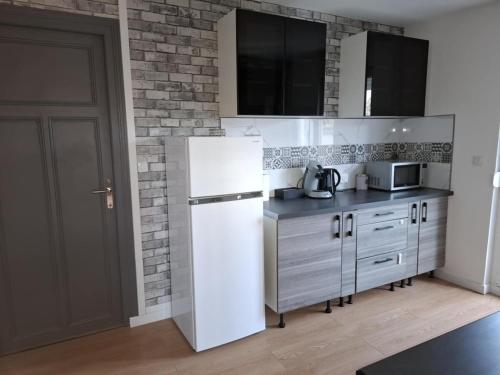 a kitchen with a white refrigerator and a brick wall at Appartement cosy in Charleville-Mézières