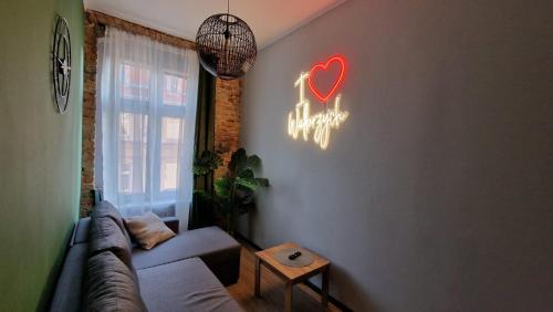 a living room with a couch and a neon heart sign at I Love Wałbrzych Apartment in Wałbrzych