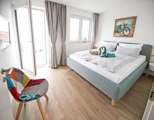 a bedroom with a bed and a chair and windows at Alte Druckerei Cicero in Norderney