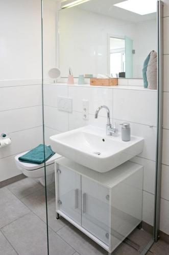 a white bathroom with a sink and a toilet at Alte Druckerei Cicero in Norderney