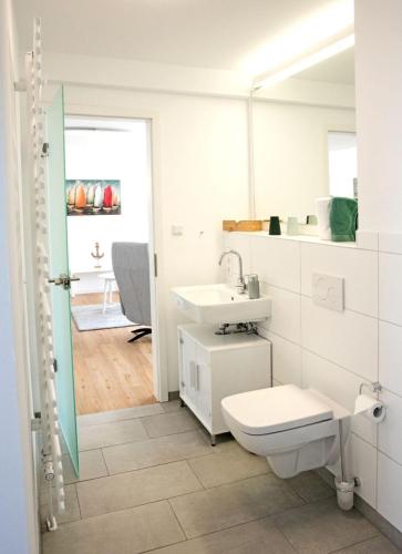 a white bathroom with a toilet and a sink at Alte Druckerei "Bodoni" in Norderney