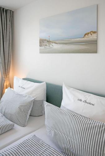 a bed with white pillows and a picture of a beach at Alte Druckerei "Bodoni" in Norderney