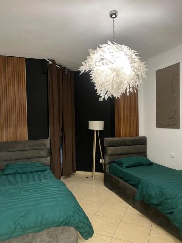 a bedroom with two beds and a chandelier at Bega's Apartment in Golem, Durrës in Golem