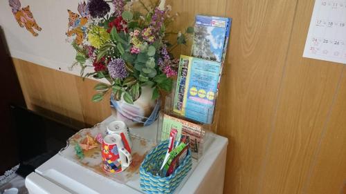 a vase of flowers sitting on top of a refrigerator at Minshuku Shizu in Onna