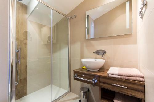 uma casa de banho com um lavatório e um chuveiro em Alison Apartments em Premantura