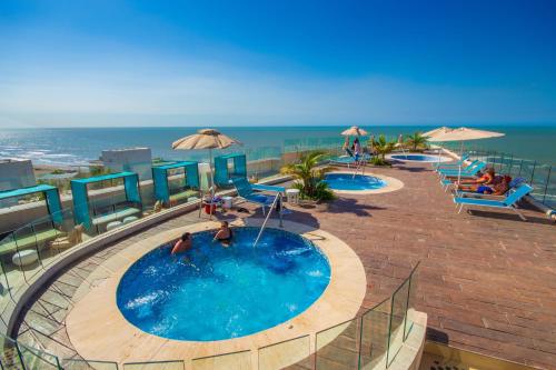 two swimming pools with umbrellas and the ocean at Radisson Cartagena Ocean Pavillion Hotel in Cartagena de Indias