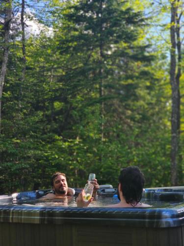 two people in a jacuzzi in a forest at Chalet Escapade, Spa, Piscine in La Patrie